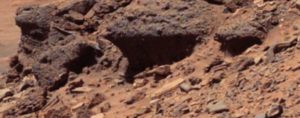 La cara de un marciano asomándose detrás de la chatarra.